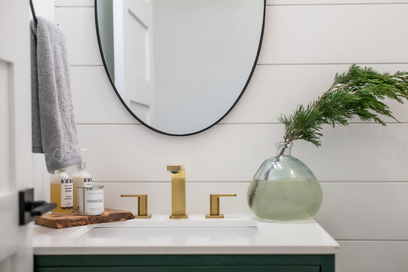Modern bathroom with gold fixtures and mirror.