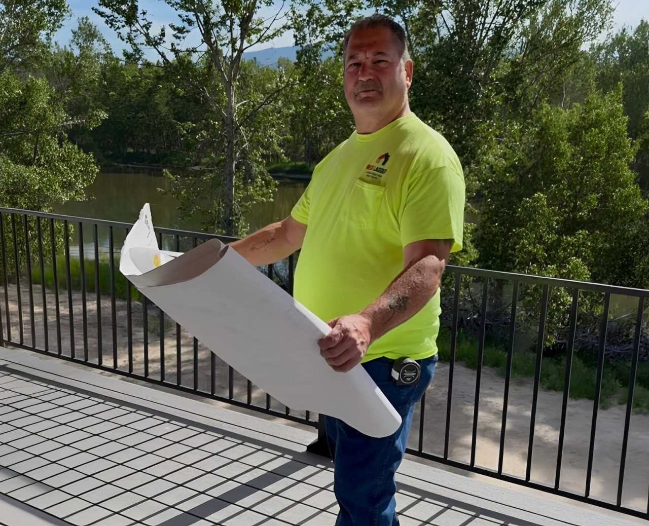 Man holding plans on a balcony outdoors.