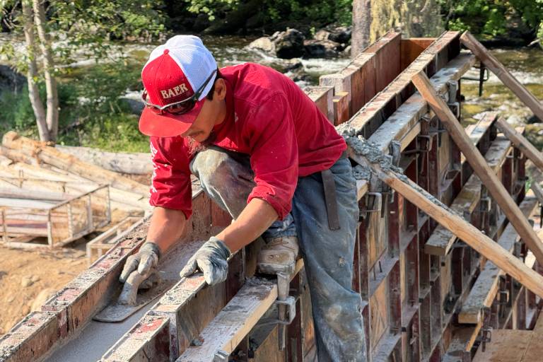 Construction worker smoothing concrete with trowel.
