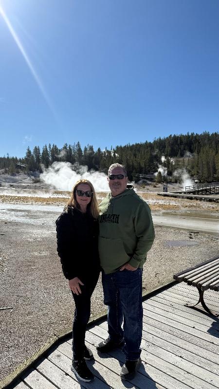 Couple posing by steaming geothermal landscape.